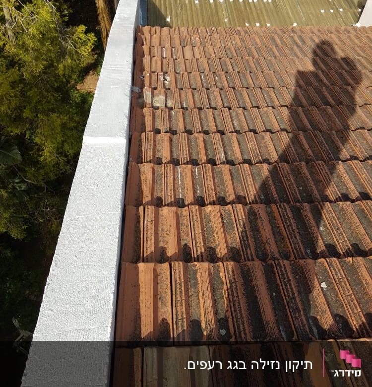 גג רעפים חום עם צל אדם על הגג